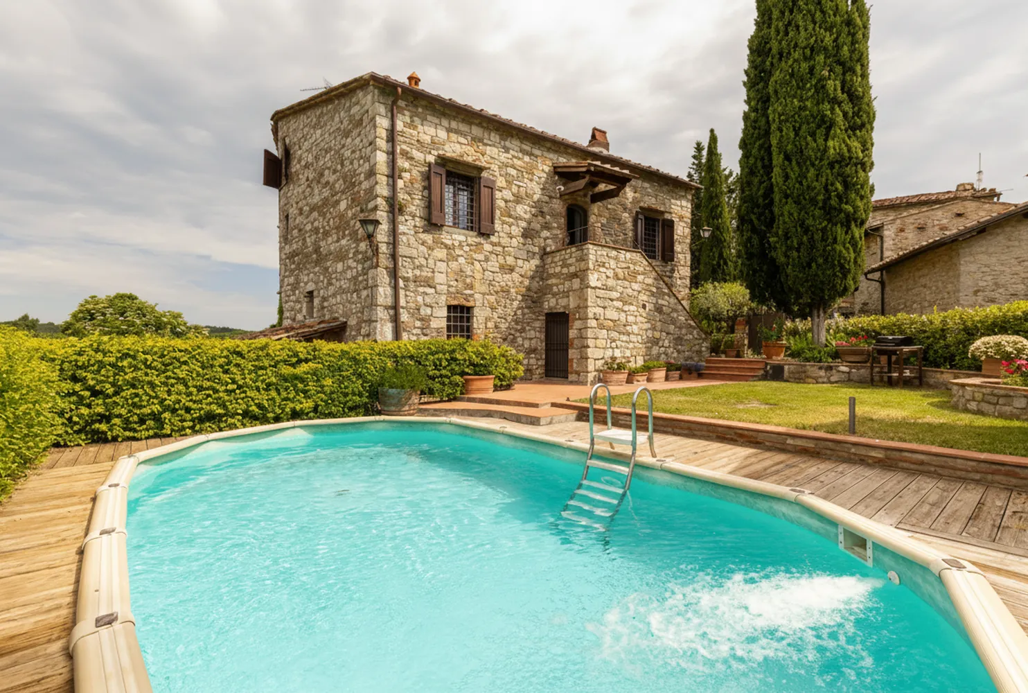 Il casale in pietra con la piscina privata e i cipressi nel giardino